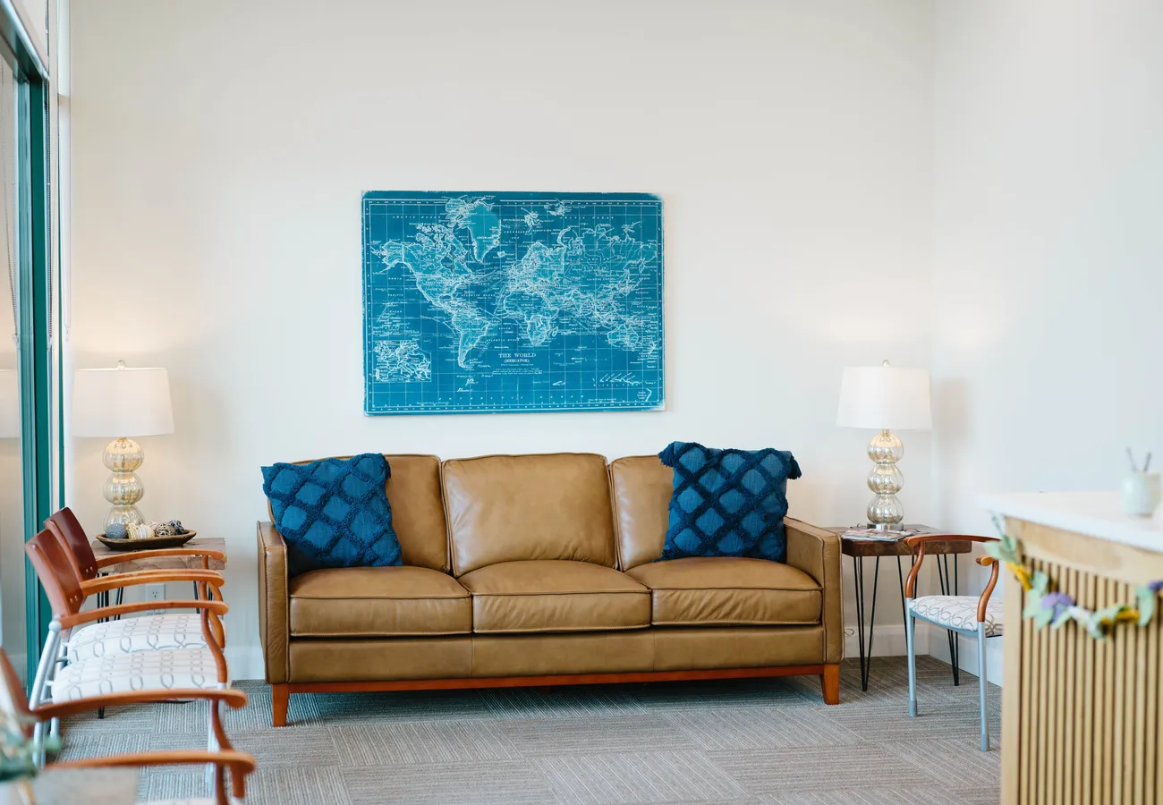 Comfortable waiting lounge at CrossPointe Dental with a leather sofa and warm décor